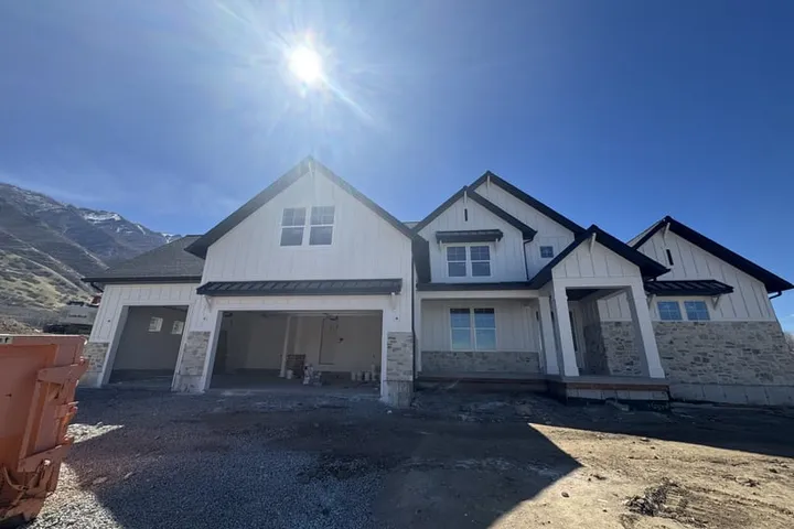 The new two-story home securing the Santaquin bridge loan, with white board-and-batten siding and stone accents