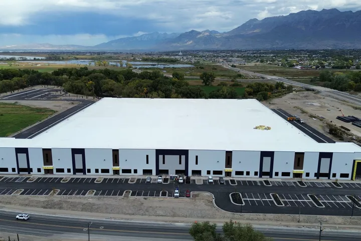 Aerial view of the finished NuSkin warehouse and parking lot in Provo, Utah, with the Wasatch Mountains behind, October 2026